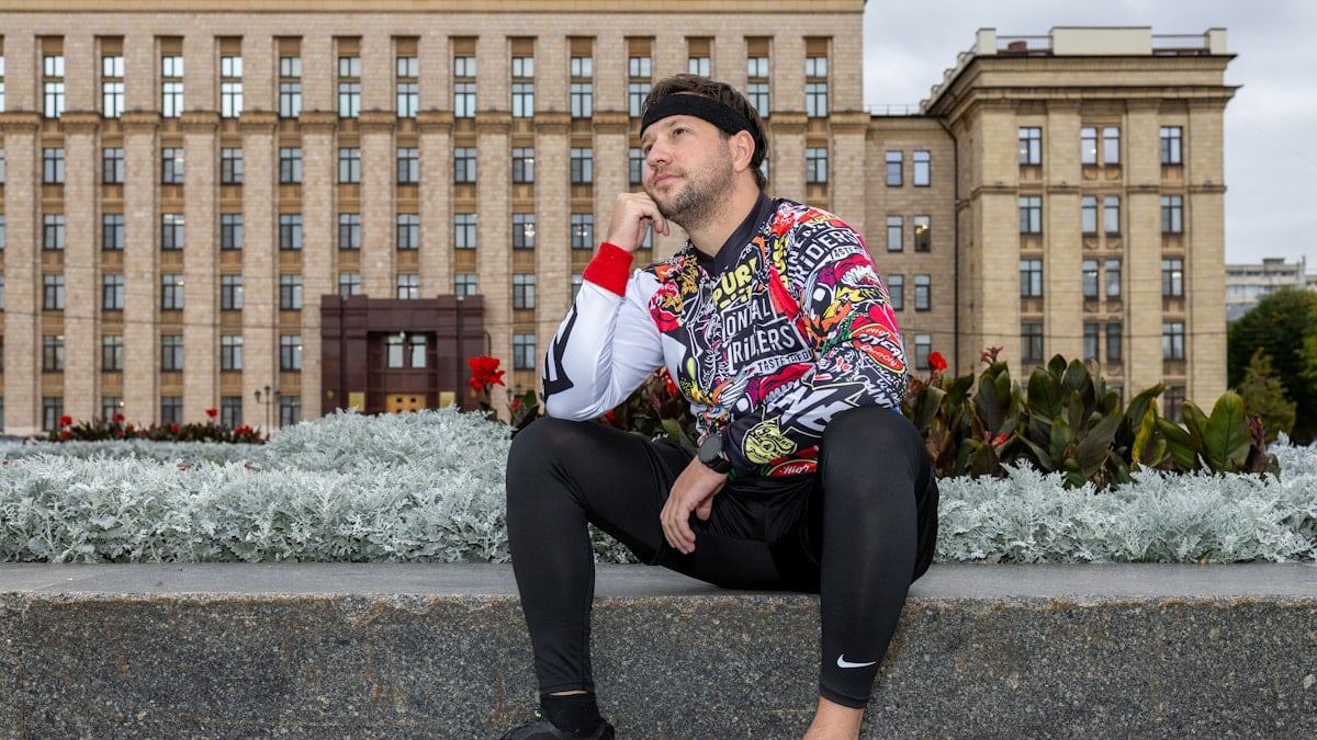 Man in colorful sweatshirt sitting in front of building